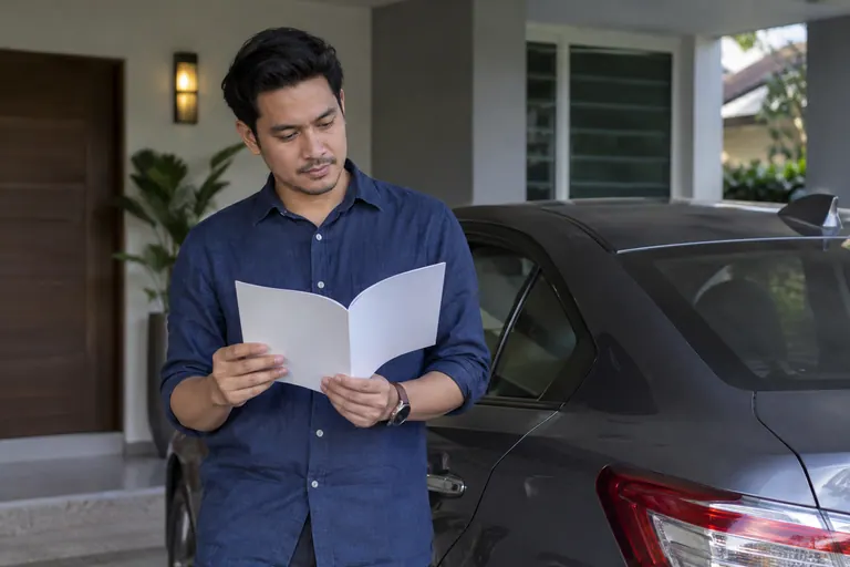Pelanggan membaca buku kosong di sebelah kereta diparkir