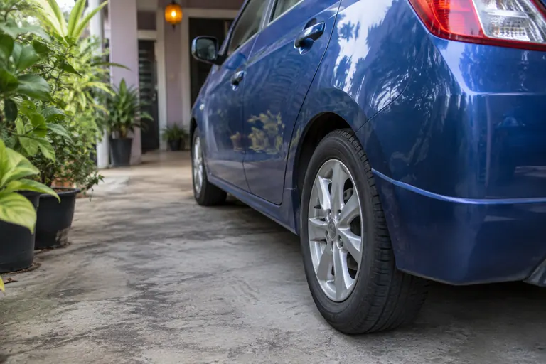 Rear wheel and side of blue hatchback parked at home
